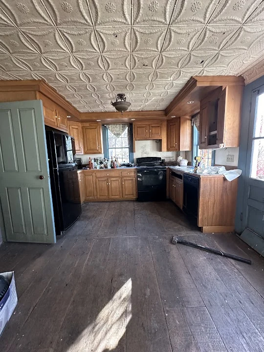 Main Street kitchen before renovation, with wood cabinets and worn flooring.