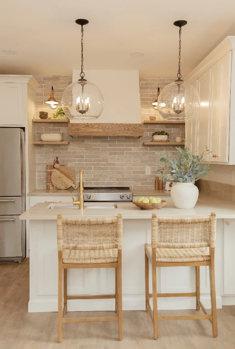 Tolland Stage kitchen after renovation, with warm wood shelves, glass pendants and woven chairs.