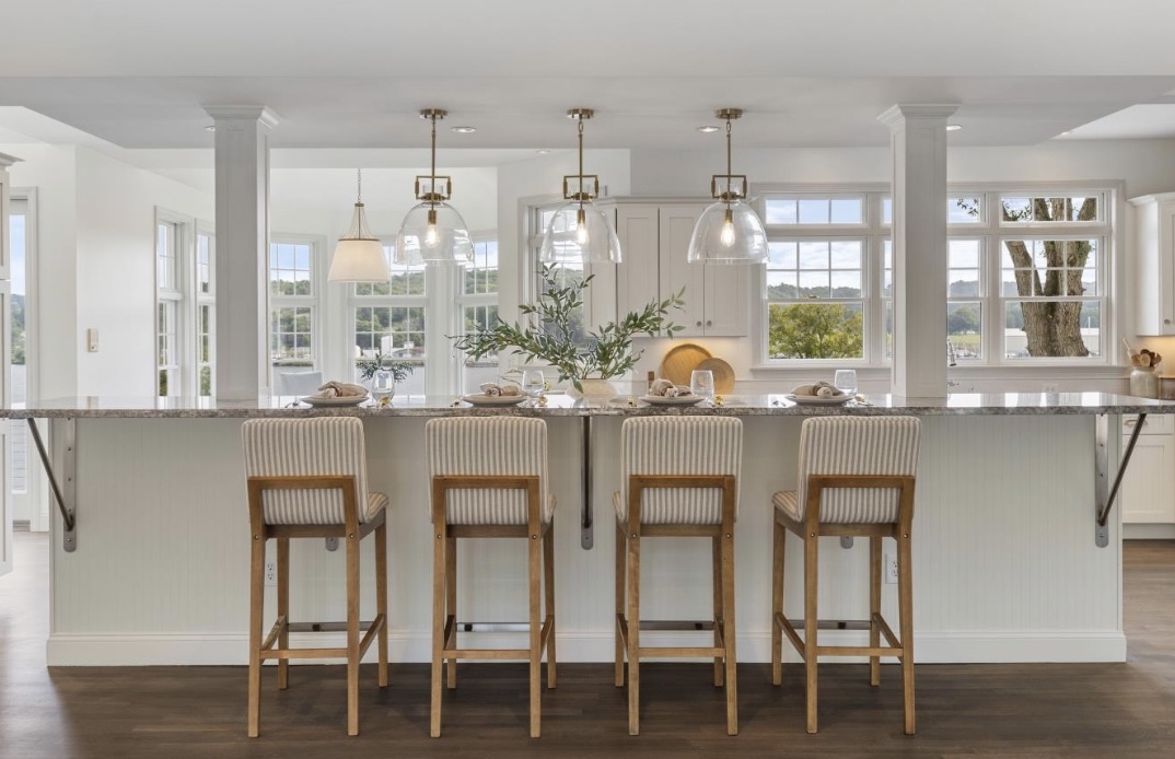 Waterford kitchen with glass pendant lights, a long island and four striped upholstered chairs.